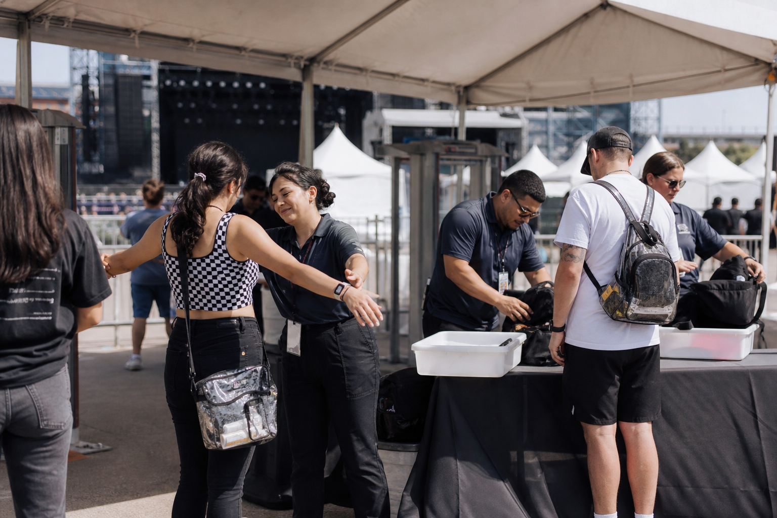Venue entry checkpoint with screening lanes and bag inspection tables before event entry.